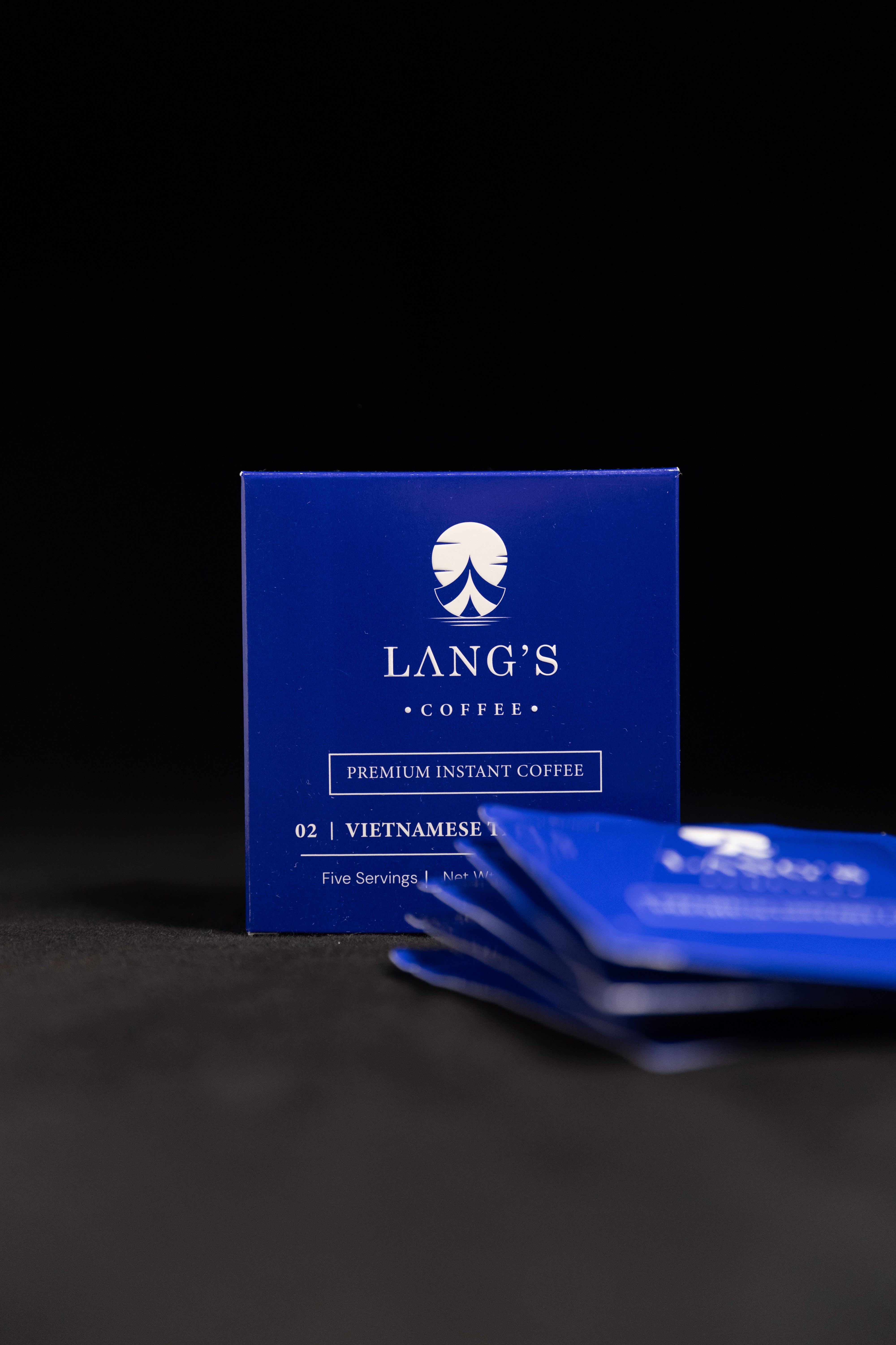 Blue packaging of Lang's Coffee on a dark background