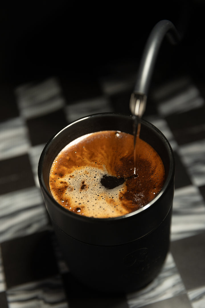 Black coffee cup with a spoon on a checkered tablecloth